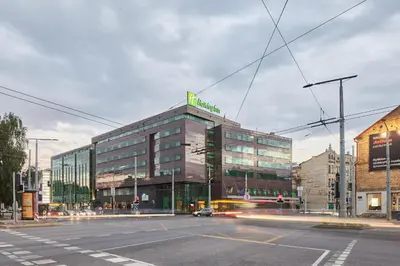 a large glass building with a green sign on top of it at Holiday Inn Vilnius by IHG in Vilnius