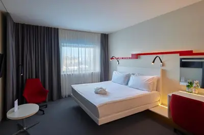 a hotel room with a bed and a red chair at Holiday Inn Vilnius by IHG in Vilnius