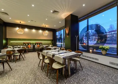 a restaurant with tables and chairs and a large window at Holiday Inn Vilnius by IHG in Vilnius