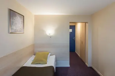 a room with a bed with a yellow pillow on it at Hotel Panorama in Vilnius