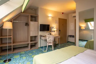 a bedroom with a bed and a desk and a tv at City Hotels Rūdninkai in Vilnius