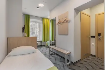 a bedroom with a bed and a window with green curtains at City Hotels Rūdninkai in Vilnius