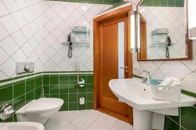 a green and white bathroom with a toilet and a sink at Grotthuss Boutique Hotel Vilnius in Vilnius