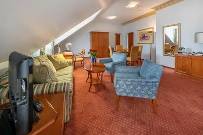a living room with a couch and chairs and a tv at Grotthuss Boutique Hotel Vilnius in Vilnius