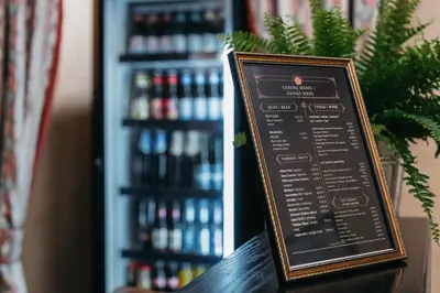 a menu board on a table with a shelf of drinks at Hotel Rinno in Vilnius