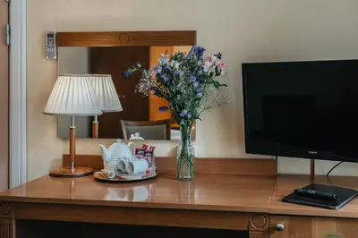 a table with a television and a vase of flowers at Hotel Rinno in Vilnius