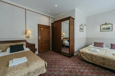a hotel room with two beds and a mirror at Hotel Rinno in Vilnius