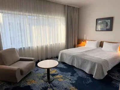 a hotel room with a bed and a chair and a window at BEST BALTIC Kaunas in Kaunas