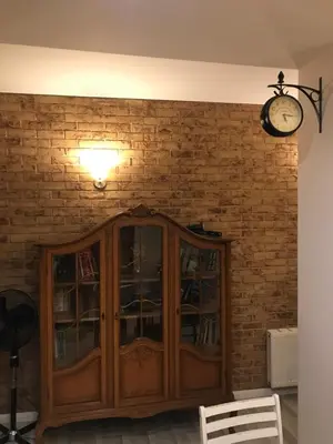 a wooden cabinet against a brick wall with a clock at Natalex Apartments in Vilnius