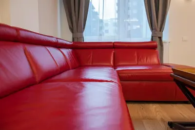a red leather couch in a room with a window at Natalex Apartments in Vilnius