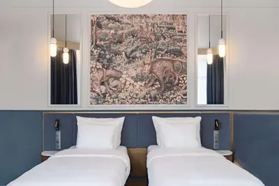 two beds in a room with a painting on the wall at Radisson Collection Astorija Hotel, Vilnius in Vilnius