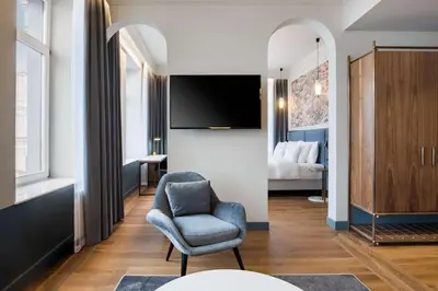 a living room with a chair and a tv at Radisson Collection Astorija Hotel, Vilnius in Vilnius