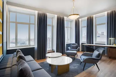 a living room with a couch and chairs and windows at Radisson Collection Astorija Hotel, Vilnius in Vilnius