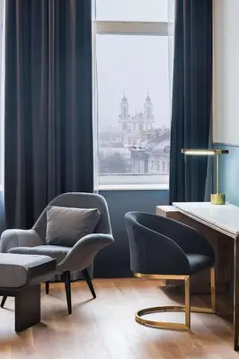 a living room with a chair and a table at Radisson Collection Astorija Hotel, Vilnius in Vilnius