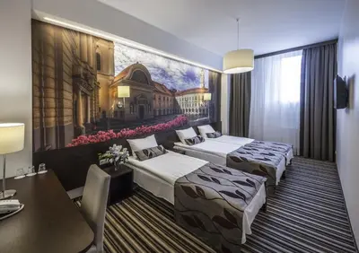 two beds in a hotel room with a painting on the wall at Vilnius City Hotel in Vilnius