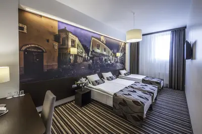 a hotel room with two beds and a painting on the wall at Vilnius City Hotel in Vilnius