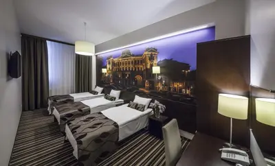 a hotel room with three beds and a picture of a building at Vilnius City Hotel in Vilnius