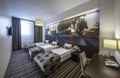 a hotel room with three beds and a table and a picture at Vilnius City Hotel in Vilnius