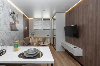 a living room with a table and a tv on a wall at Vilnius City Hotel in Vilnius