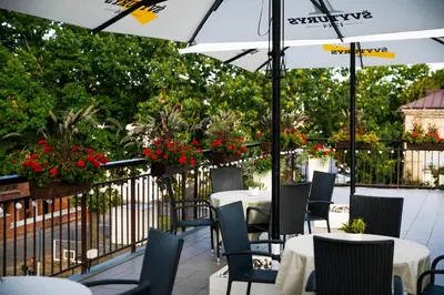 a patio with tables and chairs and an umbrella at Daugirdas Old City Hotel in Kaunas
