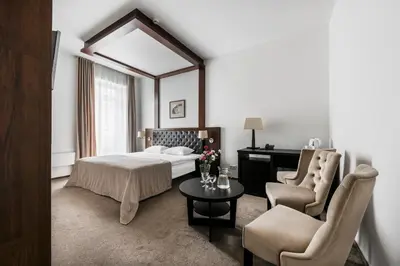 a hotel room with a bed and a table and chairs at Amberton Cozy Hotel Kaunas in Kaunas