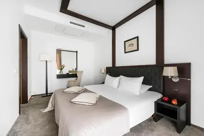 a bedroom with a large white bed with a black headboard at Amberton Cozy Hotel Kaunas in Kaunas