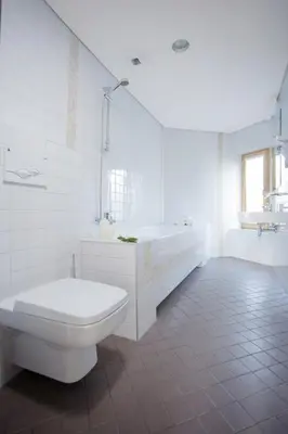 a white bathroom with a toilet and a tub and a sink at Hotel Babilonas in Kaunas