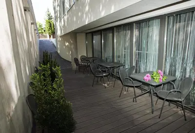a deck with tables and chairs on a building at Hotel Babilonas in Kaunas