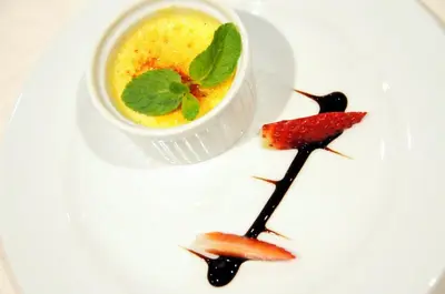 a white plate with a cup of soup and a dessert at Hotel Babilonas in Kaunas