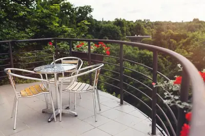 a table and chairs on a balcony with flowers at Perkuno Namai Park Hotel in Kaunas