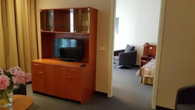 a room with a tv on a dresser with a bedroom at Perkuno Namai Park Hotel in Kaunas