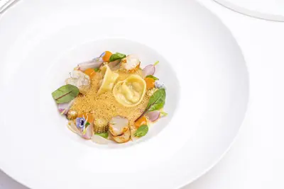 a white bowl filled with food on a white table at Stikliai Hotel - Relais & Châteaux in Vilnius