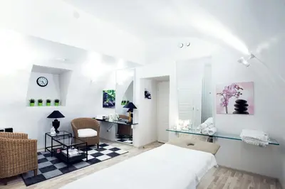 a white bedroom with a bed and a desk at Stikliai Hotel - Relais & Châteaux in Vilnius