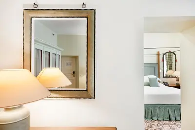 a mirror in a room with a bed and a lamp at Stikliai Hotel - Relais & Châteaux in Vilnius