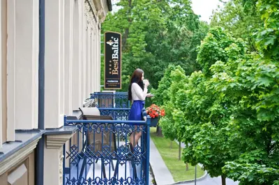 a woman standing on the balcony of a building at BEST BALTIC Hotel Druskininkai Central in Druskininkai