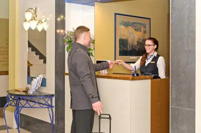 a man and a woman shaking hands at a counter at BEST BALTIC Hotel Druskininkai Central in Druskininkai