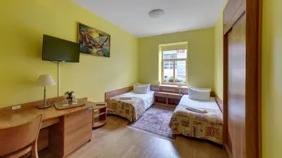 a room with two beds and a desk and a window at In Astra in Vilnius
