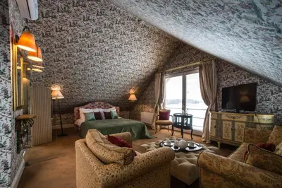 a bedroom with a bed and a couch and chairs at Apvalaus Stalo Klubas Gastro & SPA Hotel in Trakai