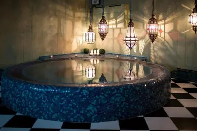 a large tub in a room with chandeliers and lights at Apvalaus Stalo Klubas Gastro & SPA Hotel in Trakai