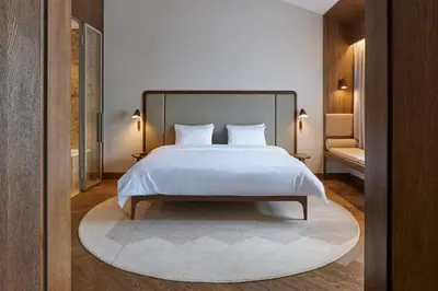 a bedroom with a large white bed with a rug at Neringa Hotel in Vilnius