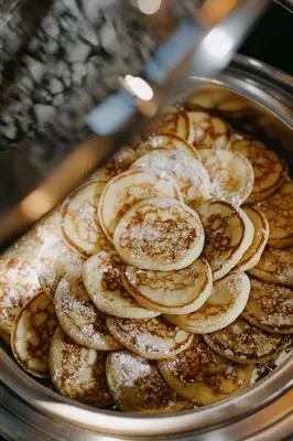 a pan filled with pancakes with powdered sugar at Neringa Hotel in Vilnius