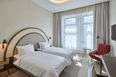 a hotel room with two beds and a red chair at Neringa Hotel in Vilnius