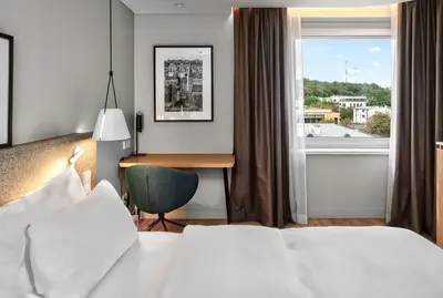 a hotel room with two beds and a desk and a window at Radisson Hotel Kaunas in Kaunas
