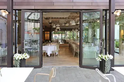 a restaurant with glass doors and tables and chairs at City Hotels Algirdas in Vilnius