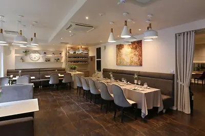 a dining room with tables and chairs and a clock at City Hotels Algirdas in Vilnius