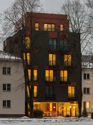a building with its lights on in the snow at Viešbutis Simpatija in Druskininkai