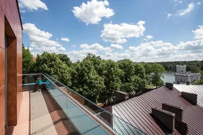 a balcony with a view of a river and trees at Viešbutis Simpatija in Druskininkai