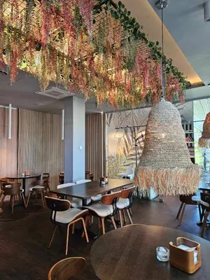 a restaurant with tables and chairs and a large chandelier at Viešbutis Simpatija in Druskininkai