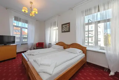 a bedroom with a bed and a tv and windows at Alexa Old Town in Vilnius