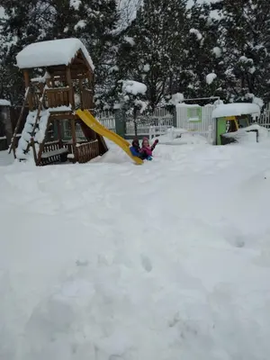 two children playing on a slide in the snow at Nemunas Tour Residence in Kaunas